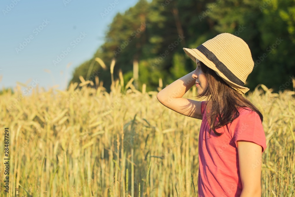 Obraz premium Portrait of beautiful girl in hat in wheat field