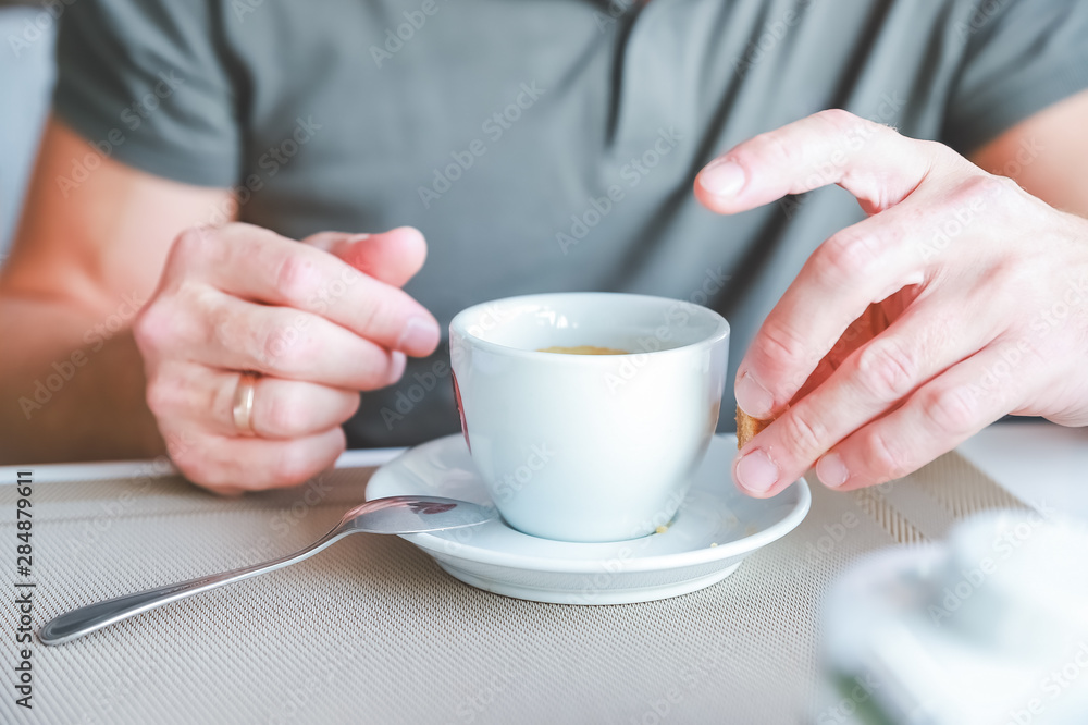 Men's hand with cup of fresh aromatic coffee at table. Men's hand with cup of fresh aromatic coffee at table.