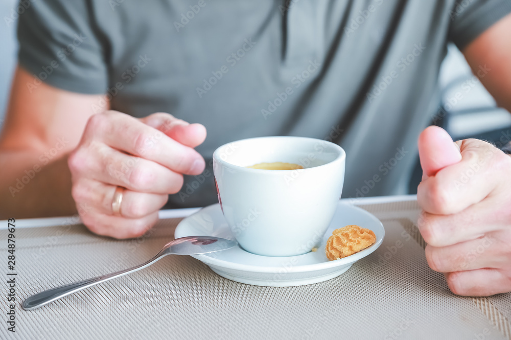 Men's hand with cup of fresh aromatic coffee at table.