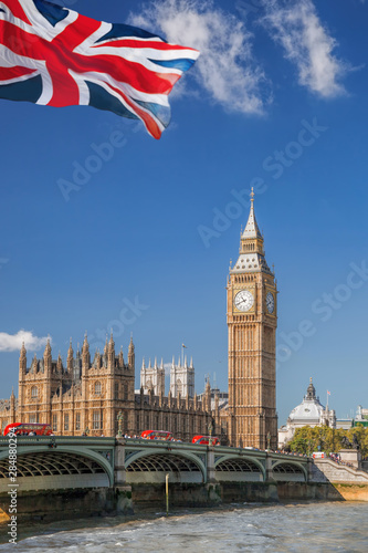 Big Ben and Houses of Parliament with red buses on bridge in London, England, UK
