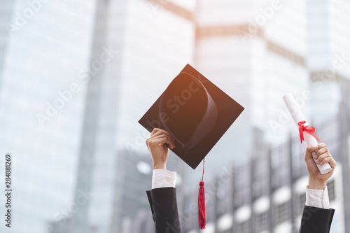 graduate are celebrating graduation. Happiness feeling hand hold show hat and diploma certificate in background School building.  Congratulation education during Commencement day University Degree.  photo