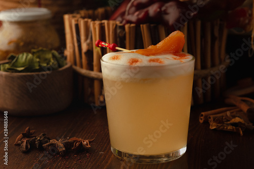 cocktail in rox decorated with a slice of mandarin on a wooden background. Background decorated with fruits and herbs.