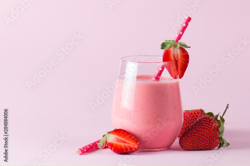 A glass of fresh strawberry smoothie on a wooden background. Summer drink shake, milkshake, juice and refreshment organic concept.