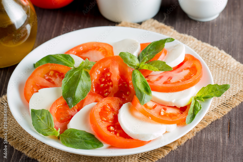 Close-up photo of caprese salad with ripe tomatoes, basil, buffalo mozzarella cheese. Italian and Mediterranean food concept. Fresh and healthy organic meal. Starter and antipasti. Close-up photo of caprese salad with ripe tomatoes, basil, buffalo mozzarella cheese. Italian and Mediterranean food concept. Fresh and healthy organic meal. Starter and antipasti.
