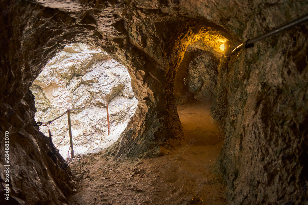 Obraz premium Poorly lit tunnel next to the narrow path along a gorge through the mountains of the Alps in the south of Germany at the border to Austria.