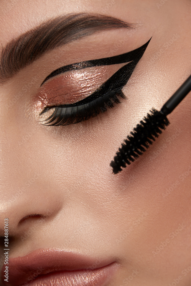 close-up eye with golden make-up and mascara brush foto de Stock Adobe Stock