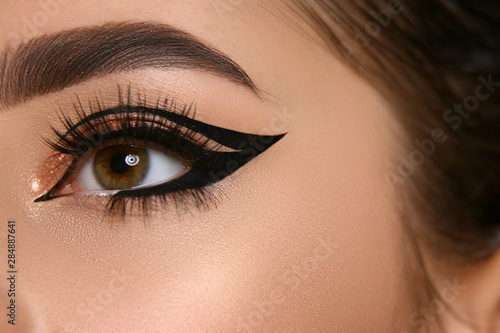 close-up of woman eye with sexy eyeliner and golden shadow photo