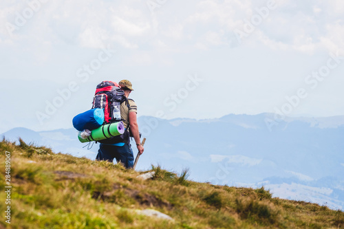 Hiker with big backpack on background of distant mountains_