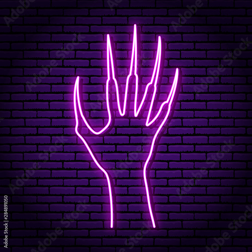 Zombie hand with claws, purple neon sign. Against the background of a brick wall. Halloween