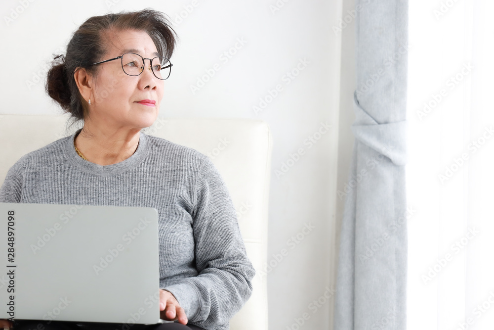 Asian Senior woman retirement using laptop computer in living room Asian Senior woman retirement using laptop computer in living room