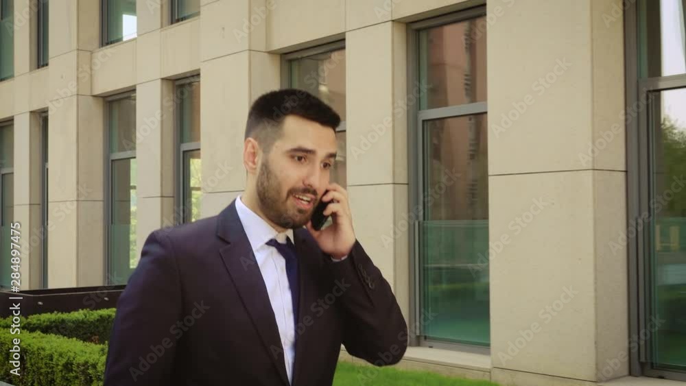Emotional smiling young man talking on smartphone outdoor. Excited businessman happy to hear good news while talking on cell phone. Close up. Emotional smiling young man talking on smartphone outdoor. Excited businessman happy to hear good news while talking on cell phone. Close up.