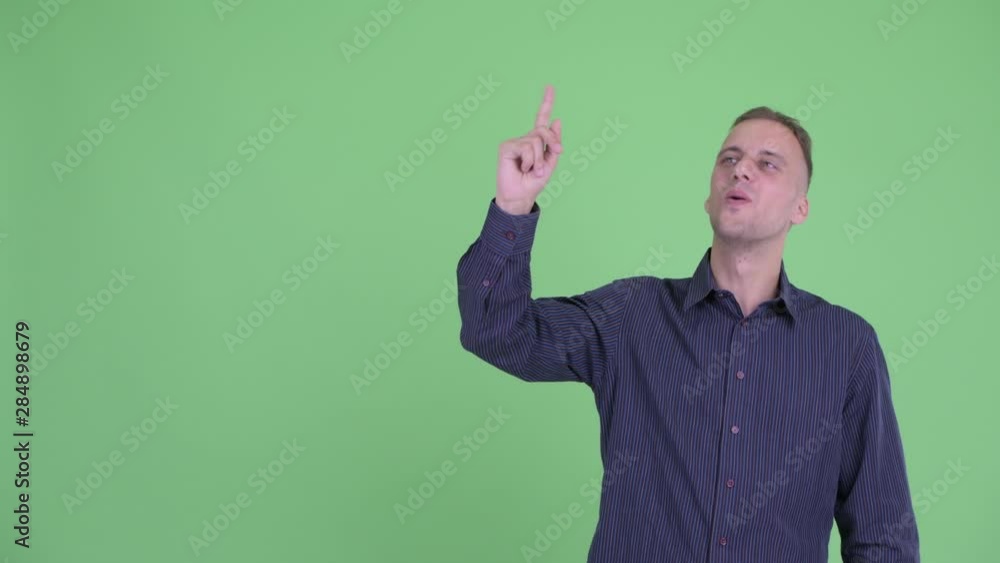 Happy handsome businessman pointing up and looking surprised Happy handsome businessman pointing up and looking surprised