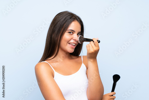 Young girl holding makeup brush over isolated background