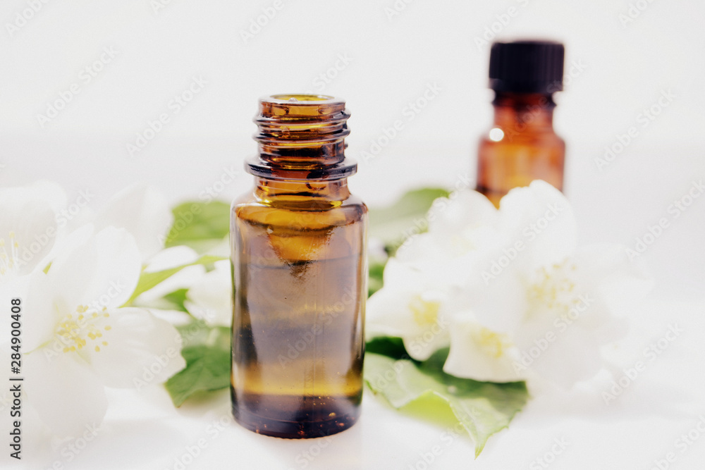 Jasmine oil or essence in a glass bottle for hair and skin. Aromatherapy and Spa concept Jasmine oil or essence in a glass bottle for hair and skin. Aromatherapy and Spa concept