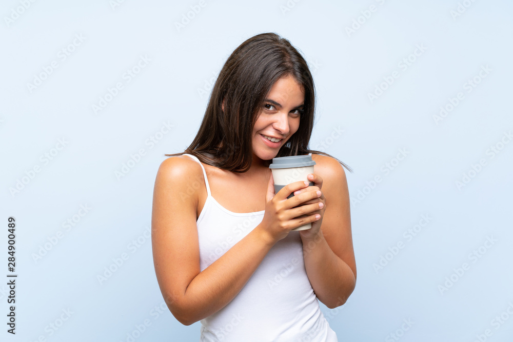 Young woman holding a take away coffee over isolated blue background Young woman holding a take away coffee over isolated blue background