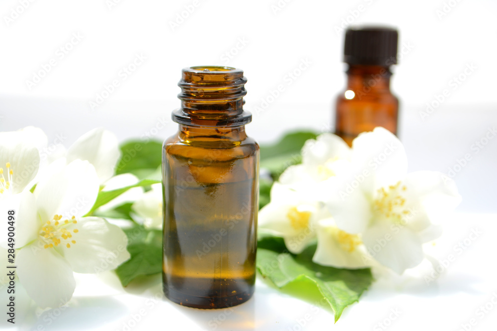 Jasmine essential oil in a glass bottle for hair and skin. Aromatherapy and Spa concept Jasmine essential oil in a glass bottle for hair and skin. Aromatherapy and Spa concept