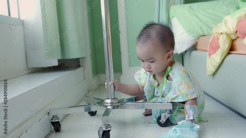 Asian baby boy playing and patient hand drip receiving a saline solution at the hospital Asian baby boy playing and patient hand drip receiving a saline solution at the hospital