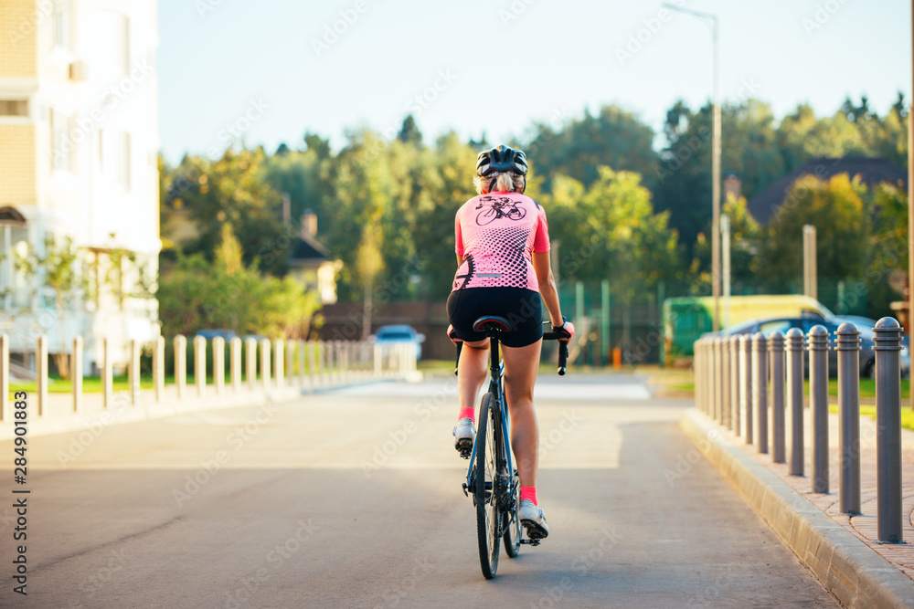 Obraz premium Picture of young woman in helmet on bike ride on summer day