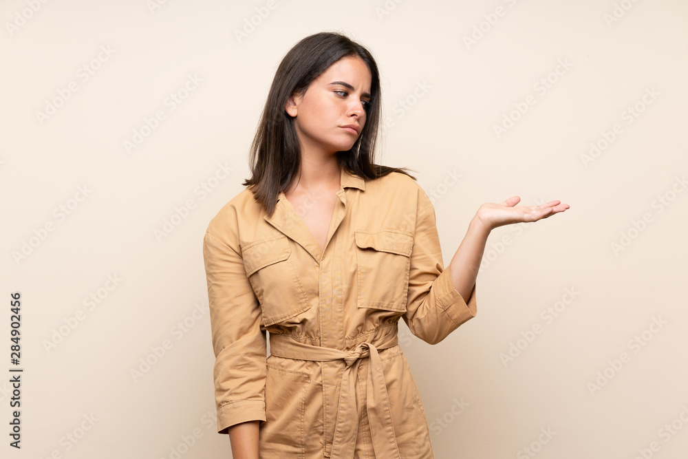 Young girl over isolated background holding copyspace with doubts Young girl over isolated background holding copyspace with doubts