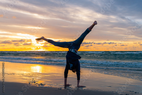 Young girl exercising on a seaside beach at sunset