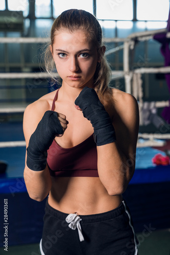 Young woman with black boxing wraps in front of ring