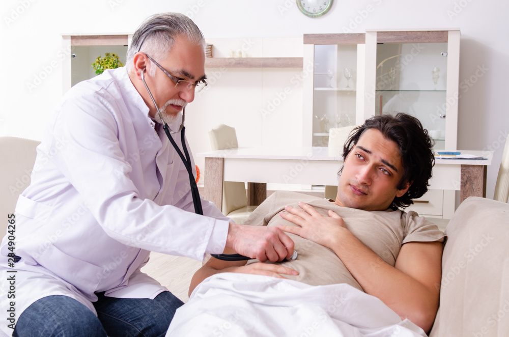 Obraz premium Old male doctor visiting young male patient