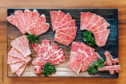 Top view of Premium Rare Slices many parts of Wagyu A5 beef with high-marbled texture on stone plate served for Yakiniku (Grilled Meat). photo