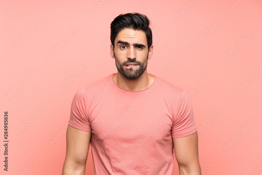 Handsome young man over isolated pink background having doubts and with confuse face expression Handsome young man over isolated pink background having doubts and with confuse face expression