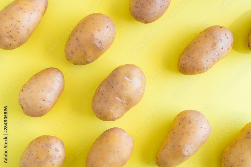 Obraz premium Raw potatoes on a yellow background.