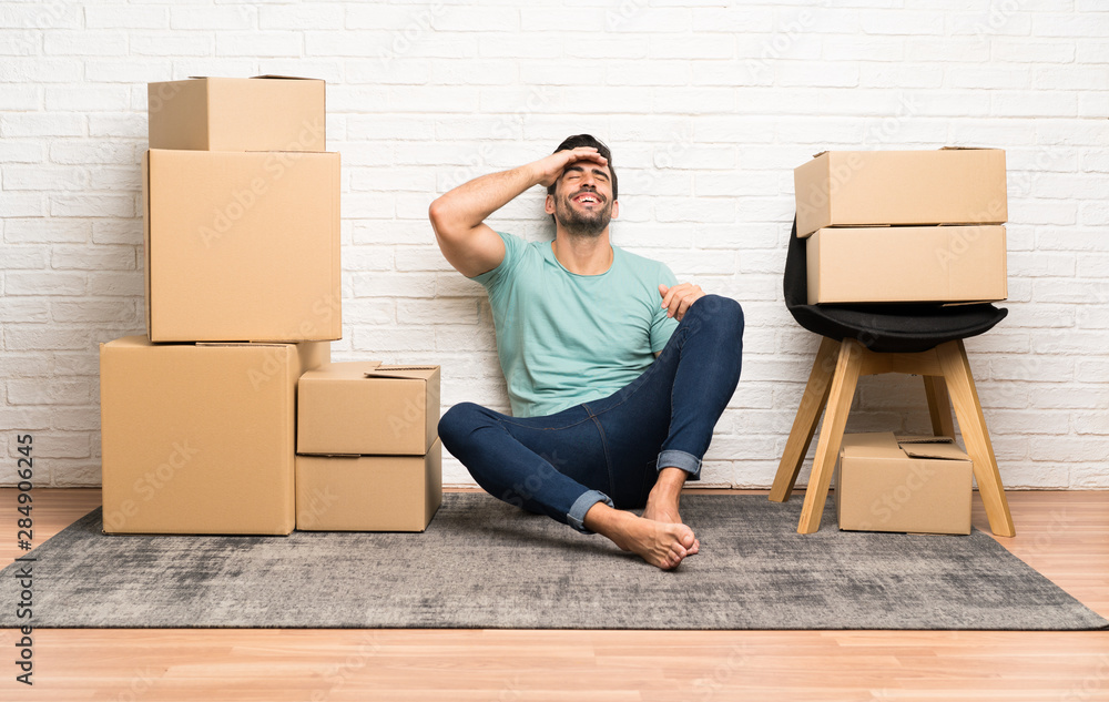 Handsome young man moving in new home among boxes laughing Handsome young man moving in new home among boxes laughing