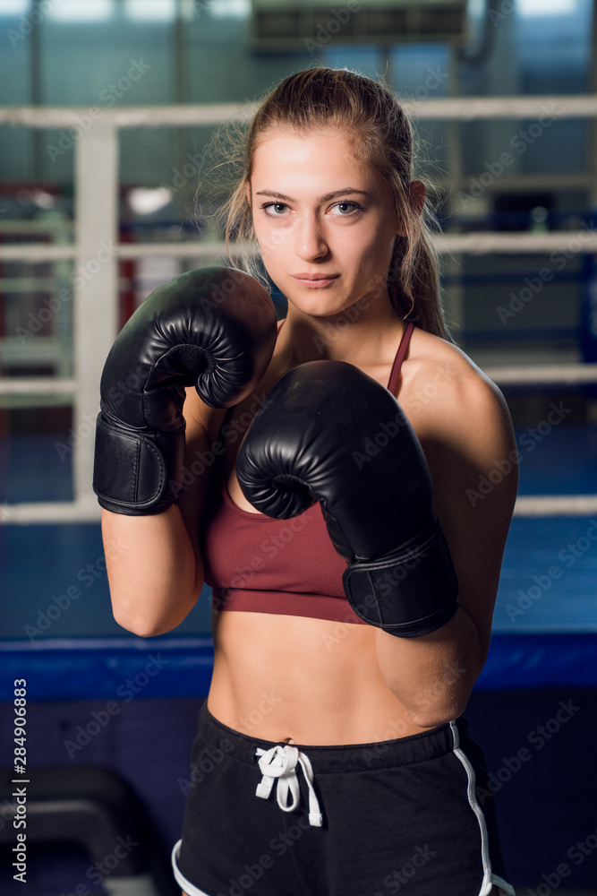 Strong woman in a black gloves standing in front of ring