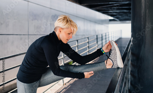 Obraz na plátně A portrait of young sportswoman doing exercise outdoors, stretching