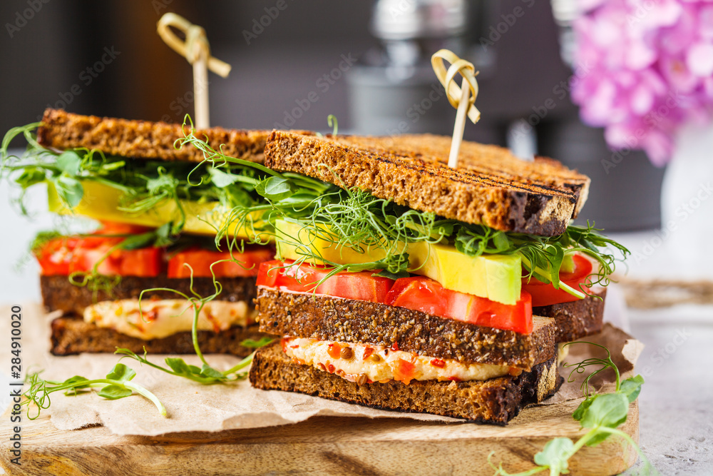 Fototapeta premium Vegan sandwich with tofu, hummus, avocado, tomato and sprouts.