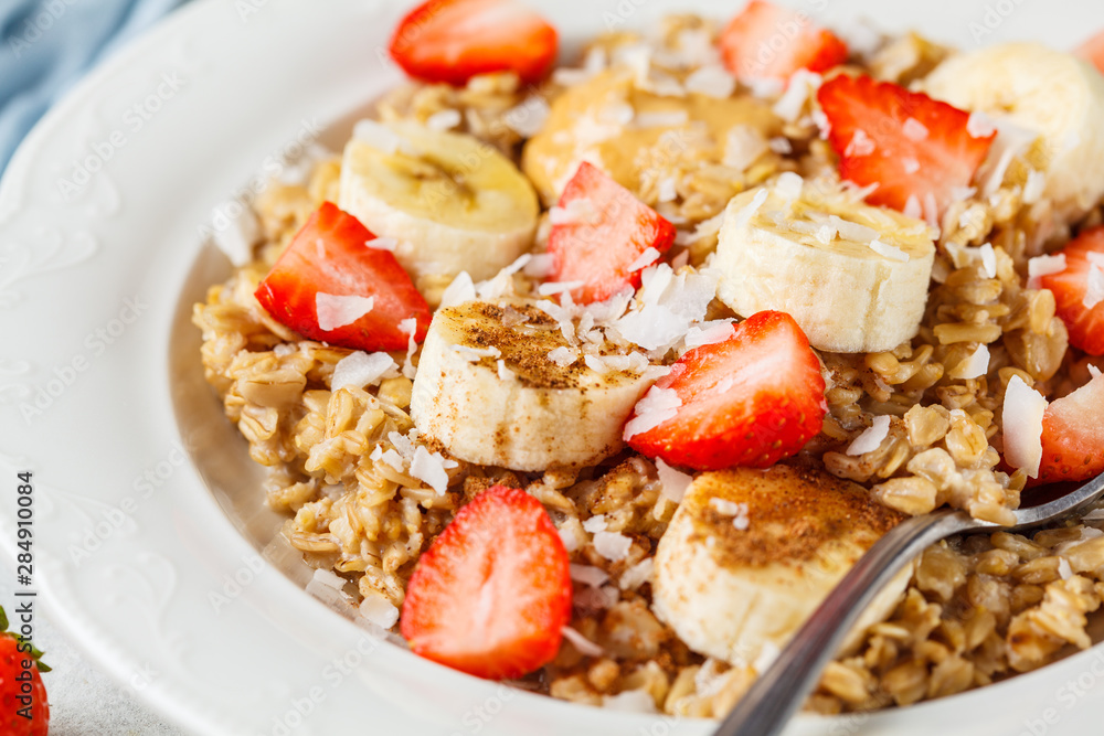 Oatmeal with banana, strawberries and peanut butter in white plate. Oatmeal with banana, strawberries and peanut butter in white plate.