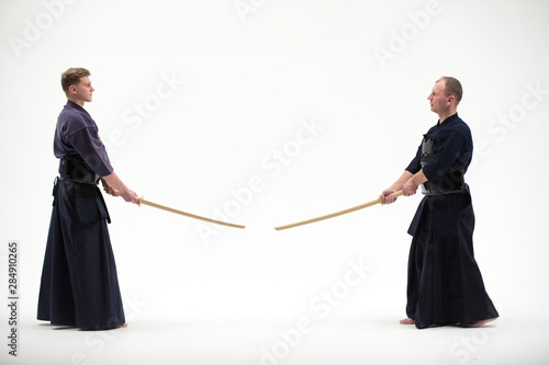 two Kendo martial arts fighters combat fighting in silhouette isolated on white bacground