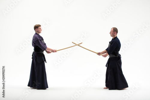 two Kendo martial arts fighters combat fighting in silhouette isolated on white bacground