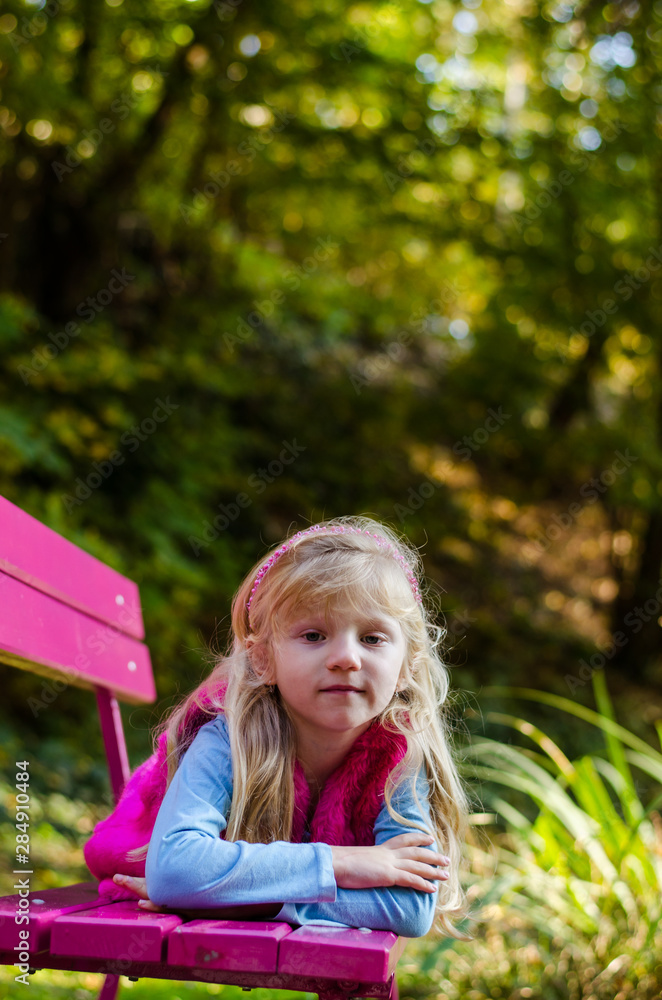 little sad child sitting in pink bench in beautiful nature little sad child sitting in pink bench in beautiful nature