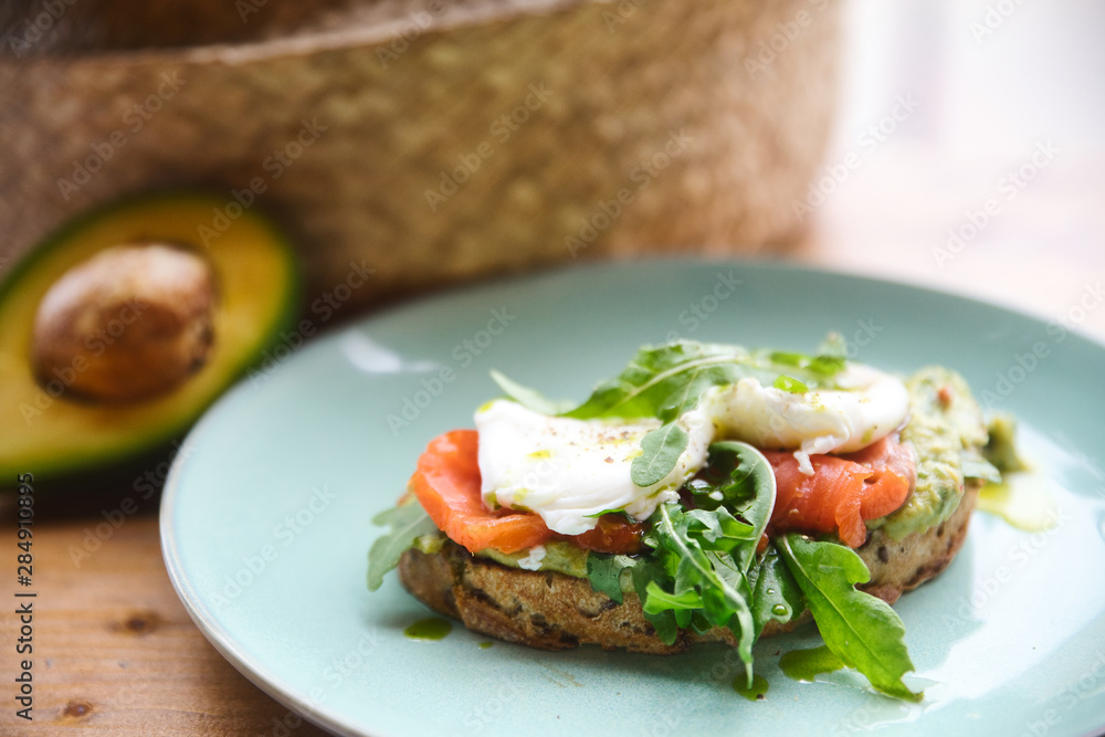Hot toast with salmon, poached egg, herbs and avocado on a plate with a black copy space flag on a skewer Hot toast with salmon, poached egg, herbs and avocado on a plate with a black copy space flag on a skewer