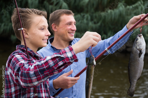 Positive father with son looking at fish on hook