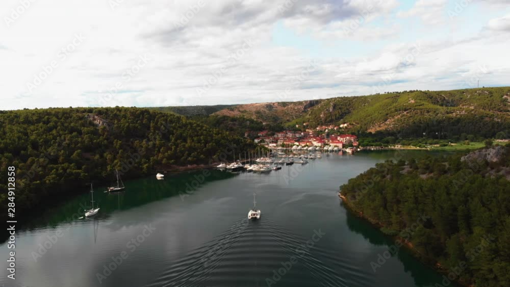 boat driving on a river towards little town boat driving on a river towards little town