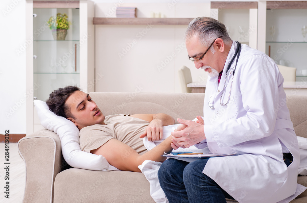 Obraz premium Old male doctor visiting young male patient