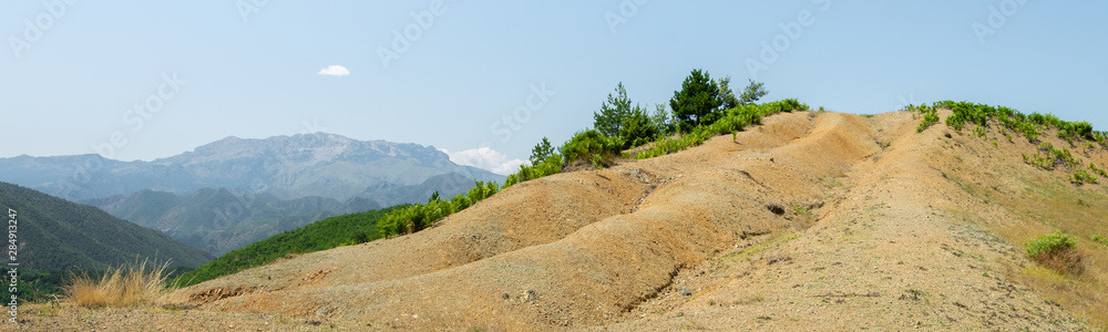Albanian nature landscape. Sandy hills with rainwater sign on the ground.