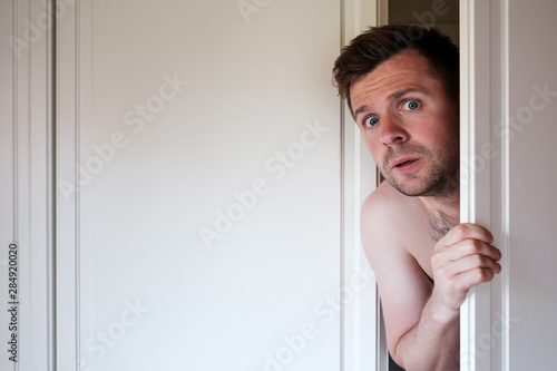 Quadro em tela Young caucasian naked man hiding in wardrobe