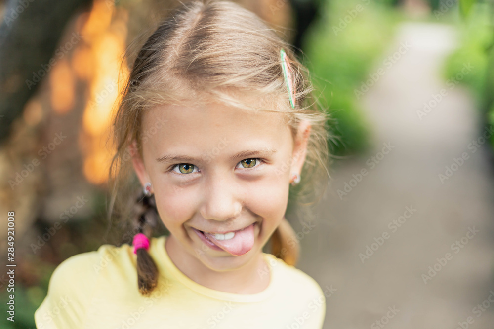 Blond little girl with yellow green eyes sticking out her tongue Blond little girl with yellow green eyes sticking out her tongue