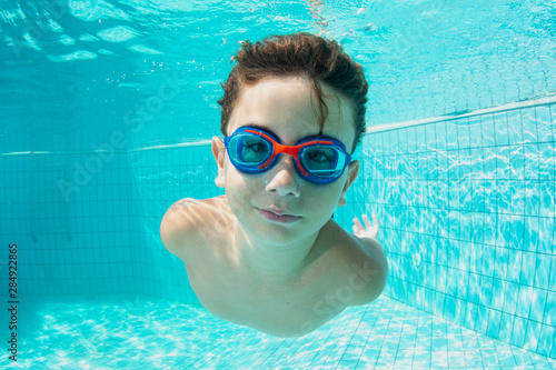 Portrait of little boy swimming underwater.