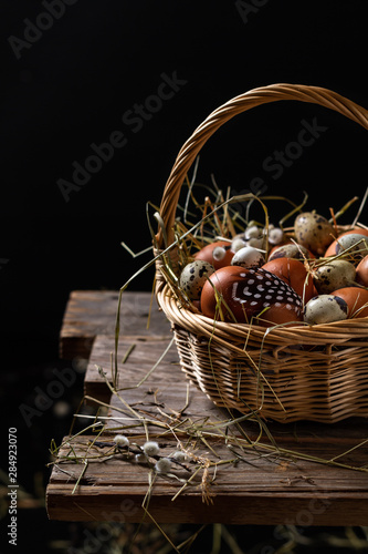 Basket of eggs on old wooden background. Brown farm eggs and quail eggs.