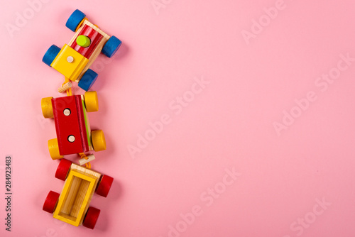 Wooden train on pink background with space for text.