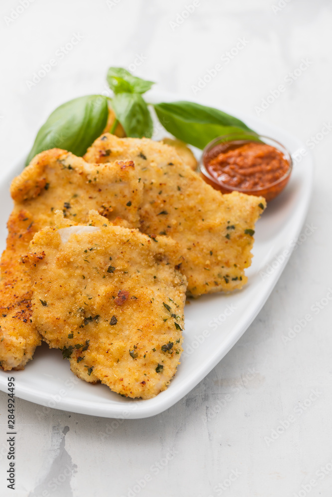 fried chicken breast with sauce on white dish on ceramic background fried chicken breast with sauce on white dish on ceramic background