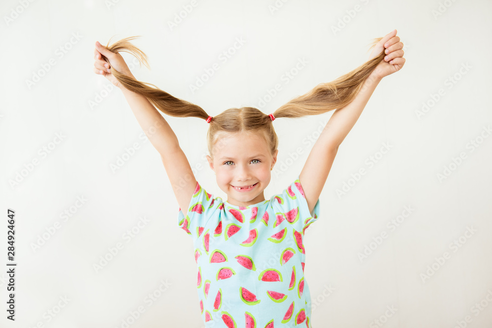 Portrait of beautiful smiling girl holding in her hands pigtails, closeup on white background Portrait of beautiful smiling girl holding in her hands pigtails, closeup on white background
