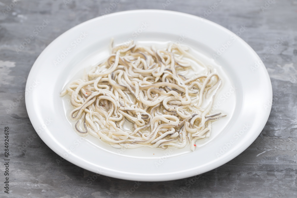 Traditional Spanish food. Gulas with oil on white plate.